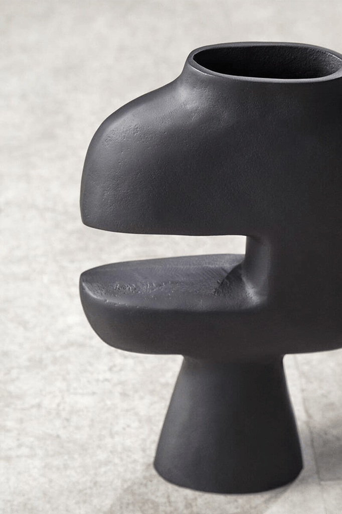 Black ceramic vase with unique design on a light gray background