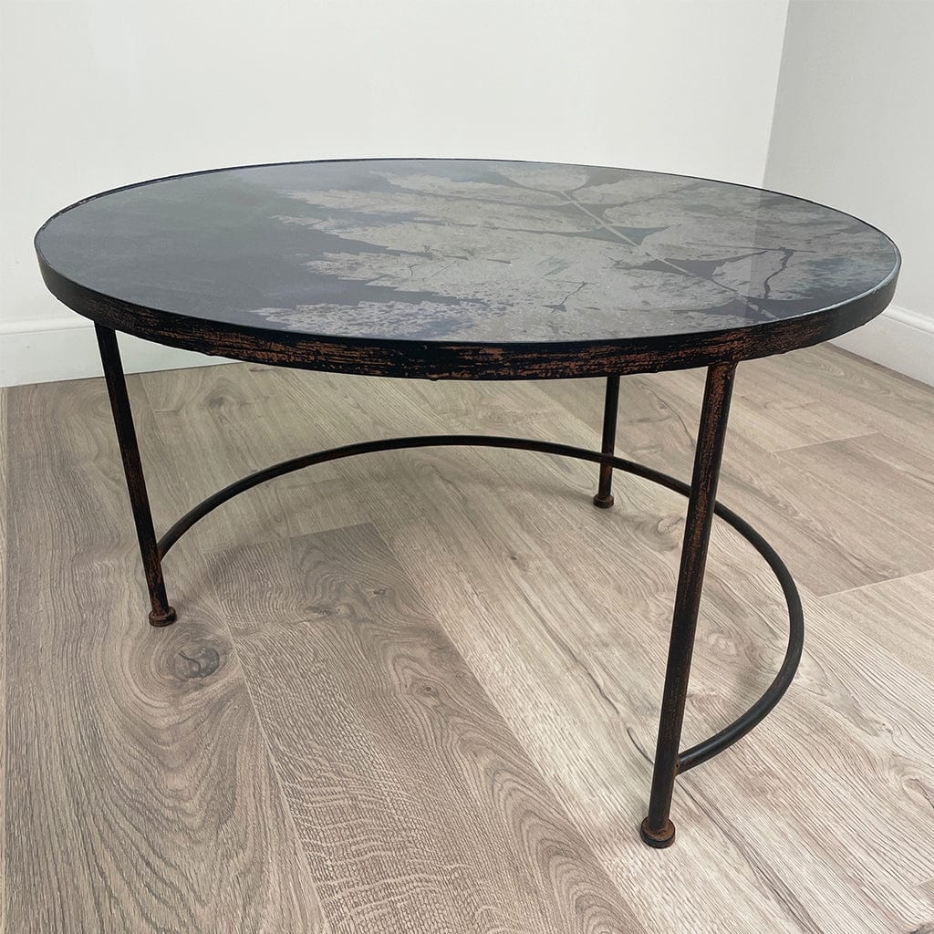 Round coffee table with a dark marble top and metal frame on a wooden floor.