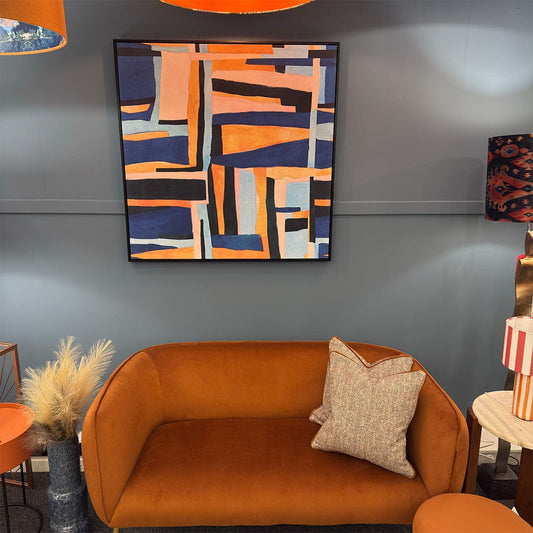 Orange sofa with a abstract art piece on the wall in a room setting.