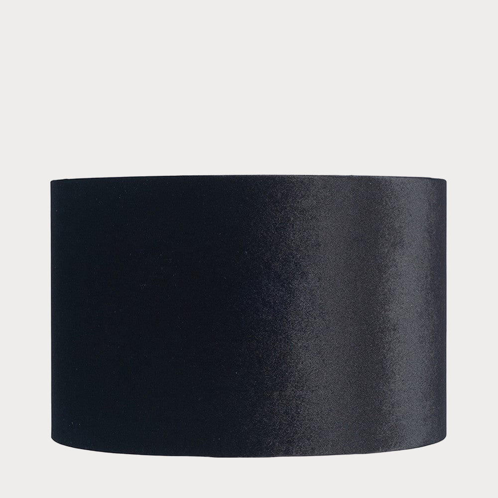 A cylindrical velvet lampshade in black color with a bronze lining, displayed against a plain background.
