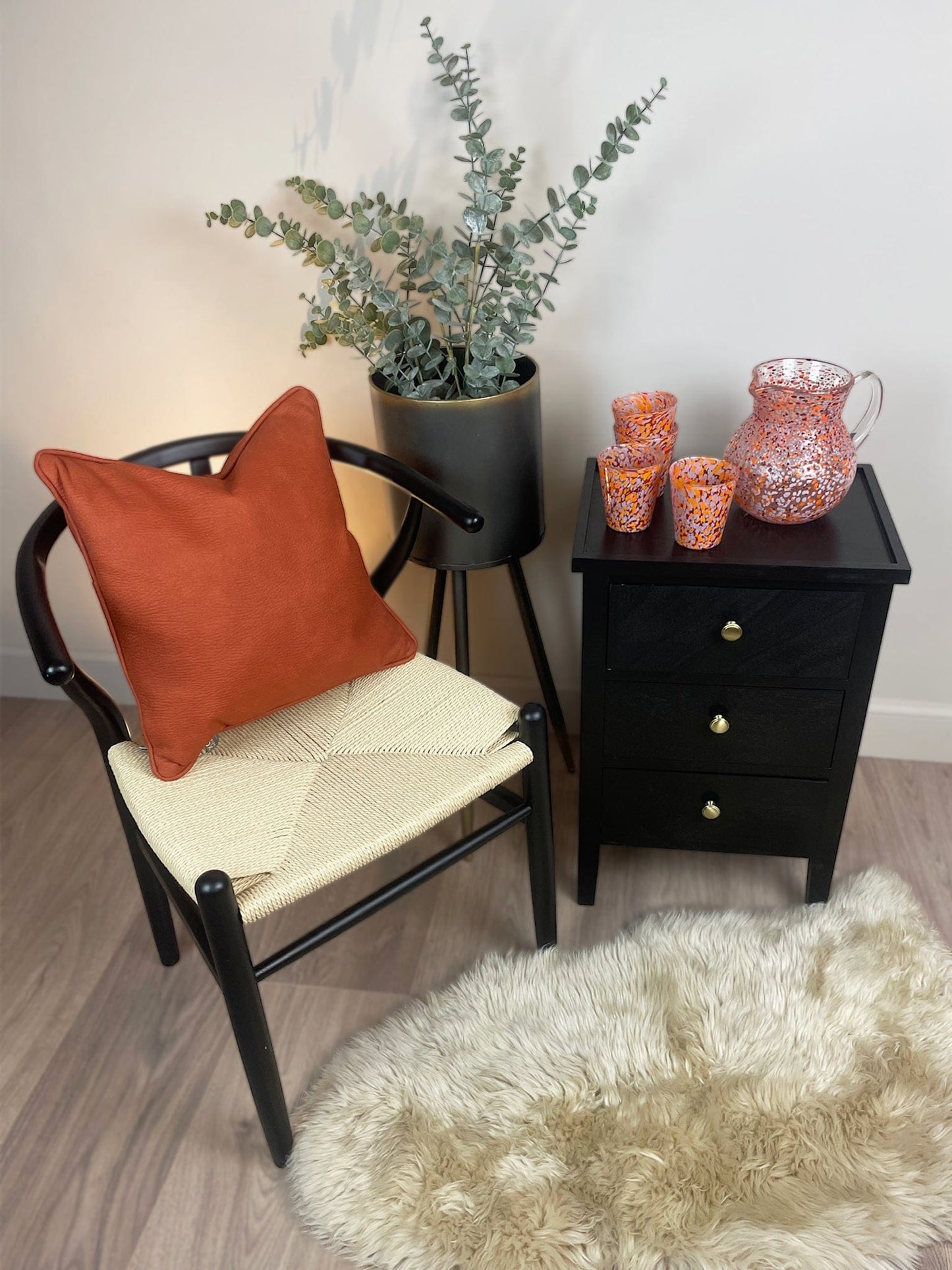 Chair with an orange cushion and a small table with decorative items in a room.