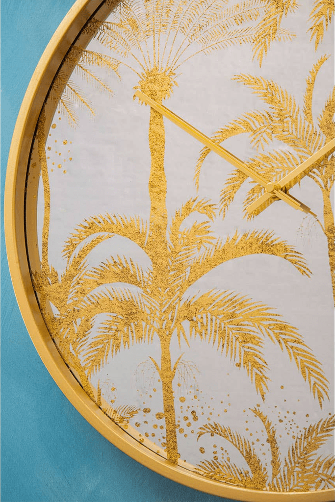 Decorative wall clock with gold palm tree design on a blue background