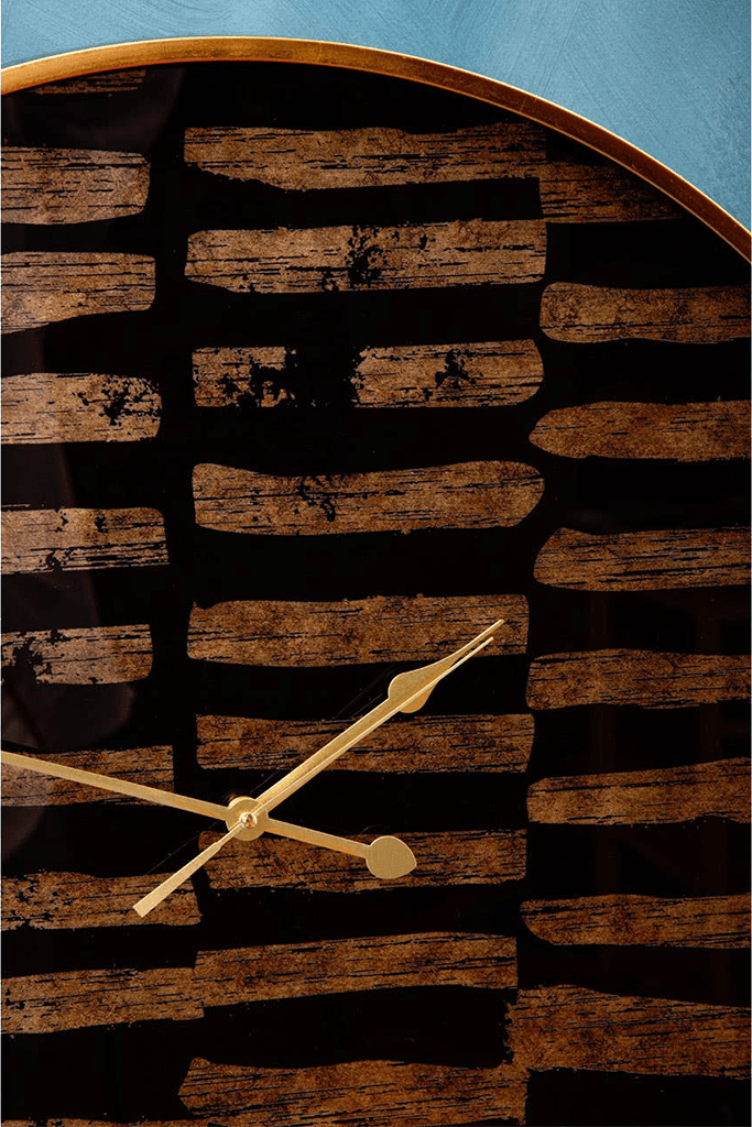 black and gold wall clock with a rustic design on a blue background