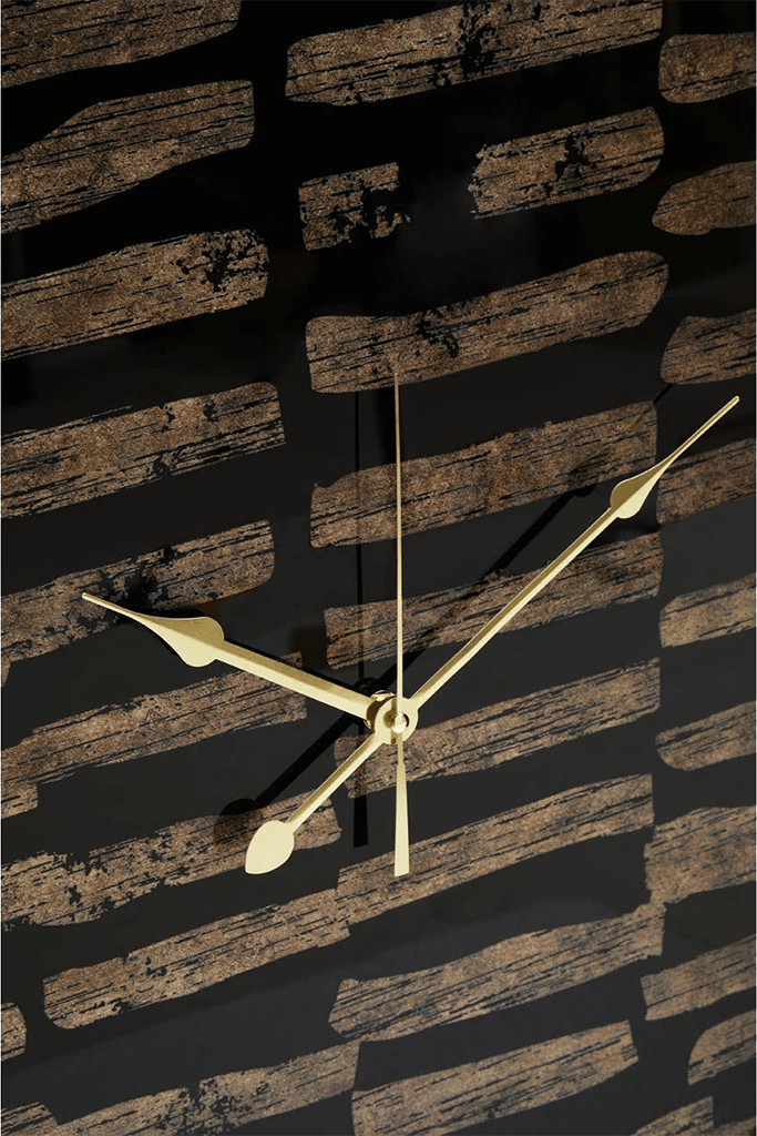 Gold clock on a textured black and brown wall