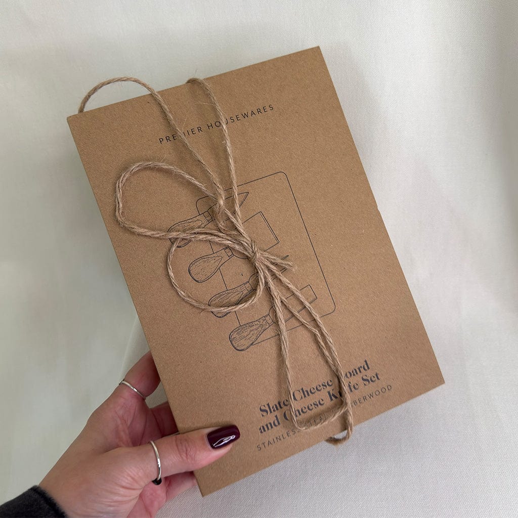 Kraft paper box with twine bow held by a hand on a light background
