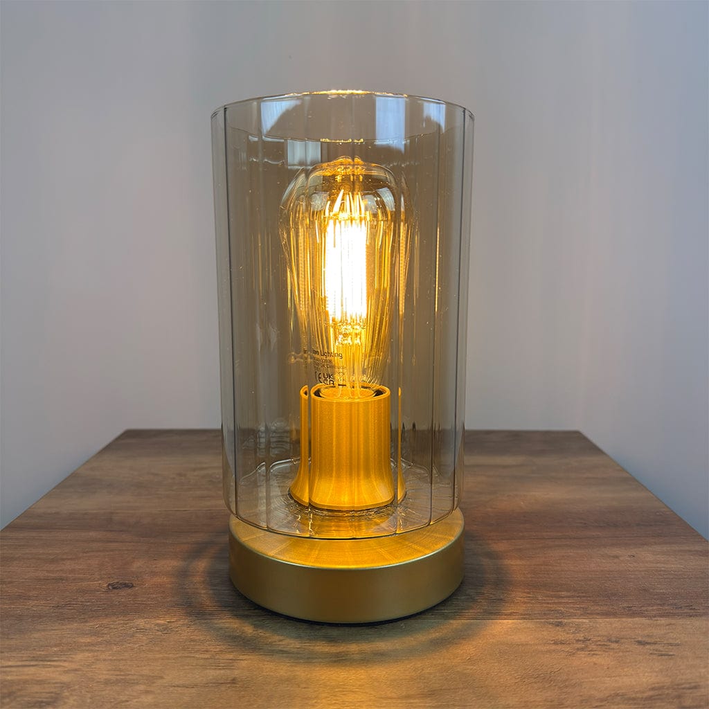 Decorative lamp with a glowing bulb inside a clear glass cover on a wooden surface.