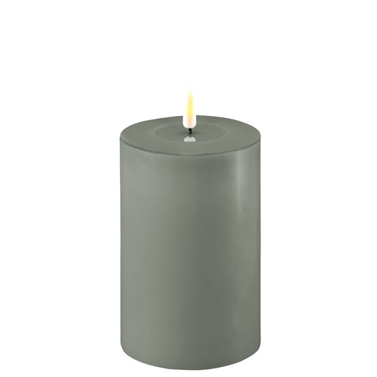A green LED candle with a realistic appearance, displaying a warm flame at the top.