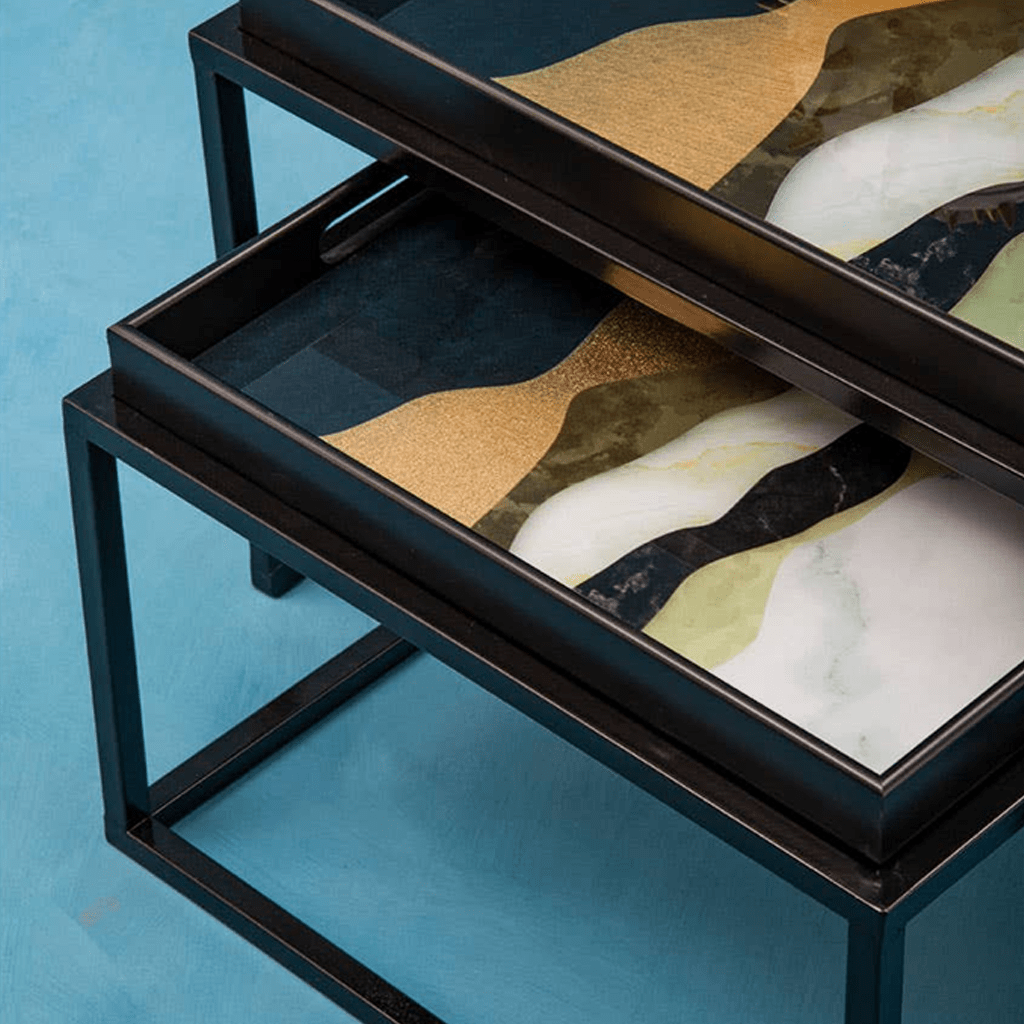 Two abstract art pieces on black metal frames against a blue background