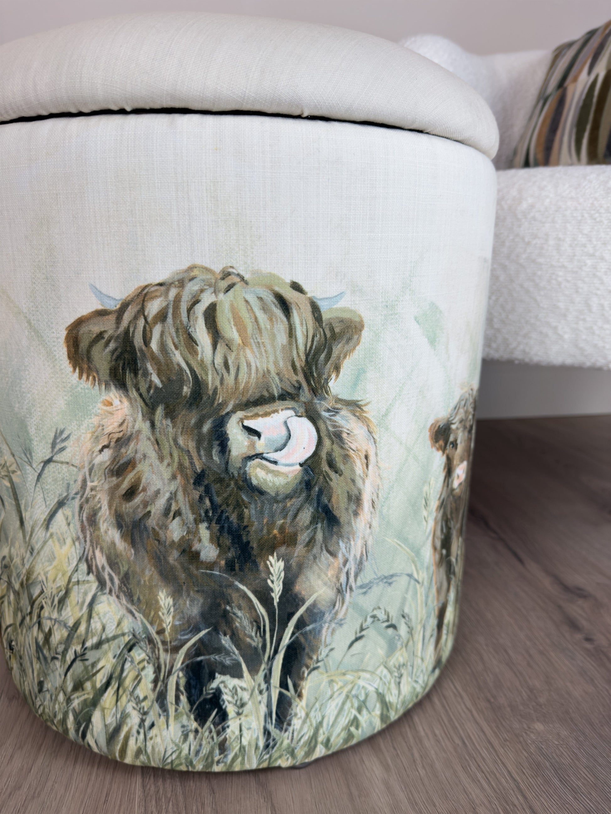 Decorative storage footstool with a cow design on a wooden floor.