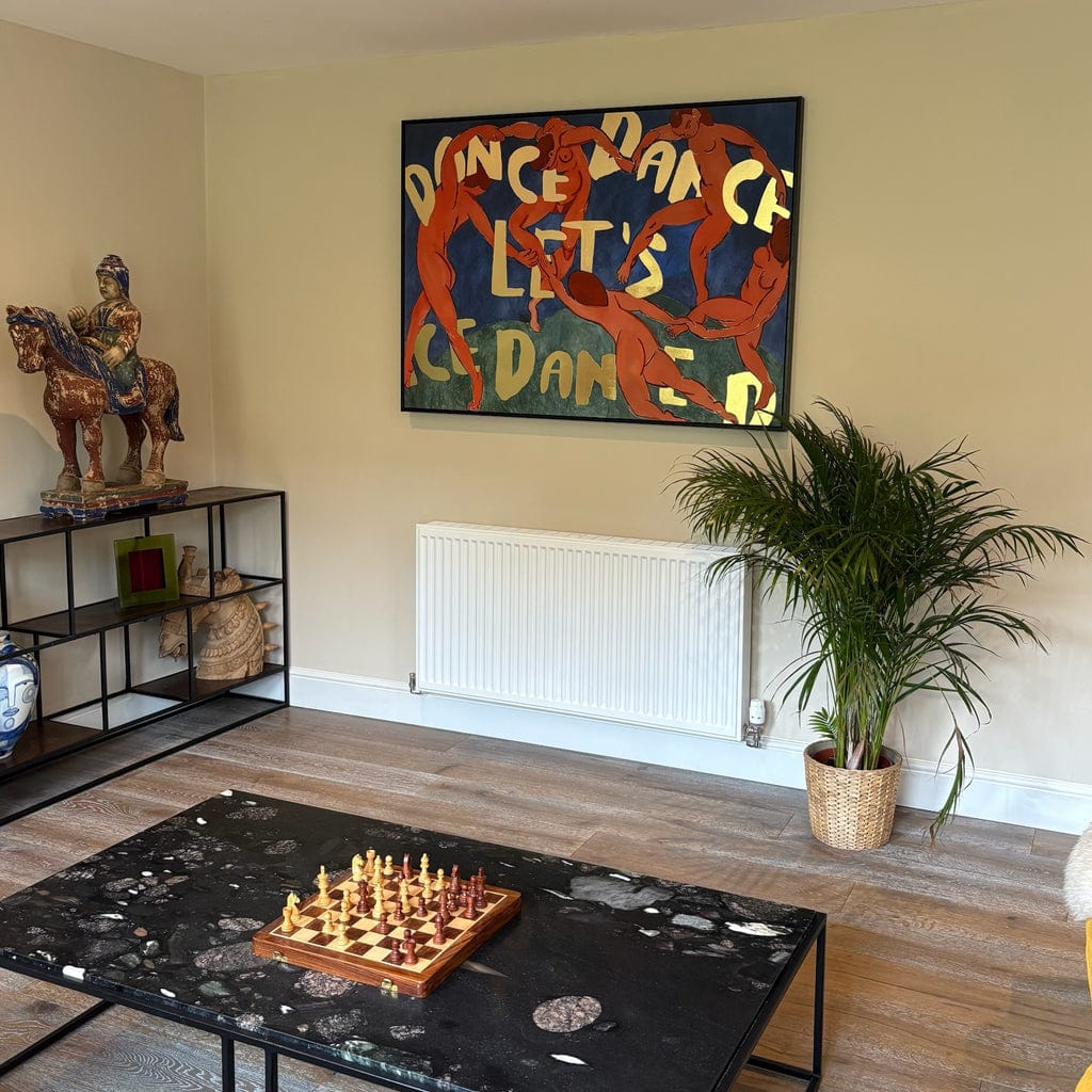Living room with a chessboard, plant, and colorful abstract painting on the wall.