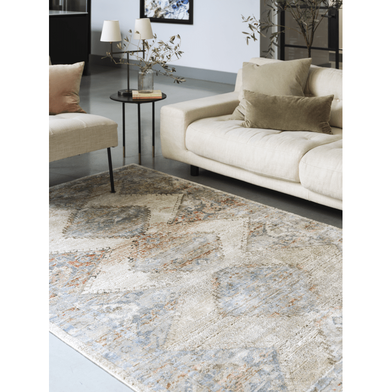 A persian style rug on a floor in a room in front of a sofa