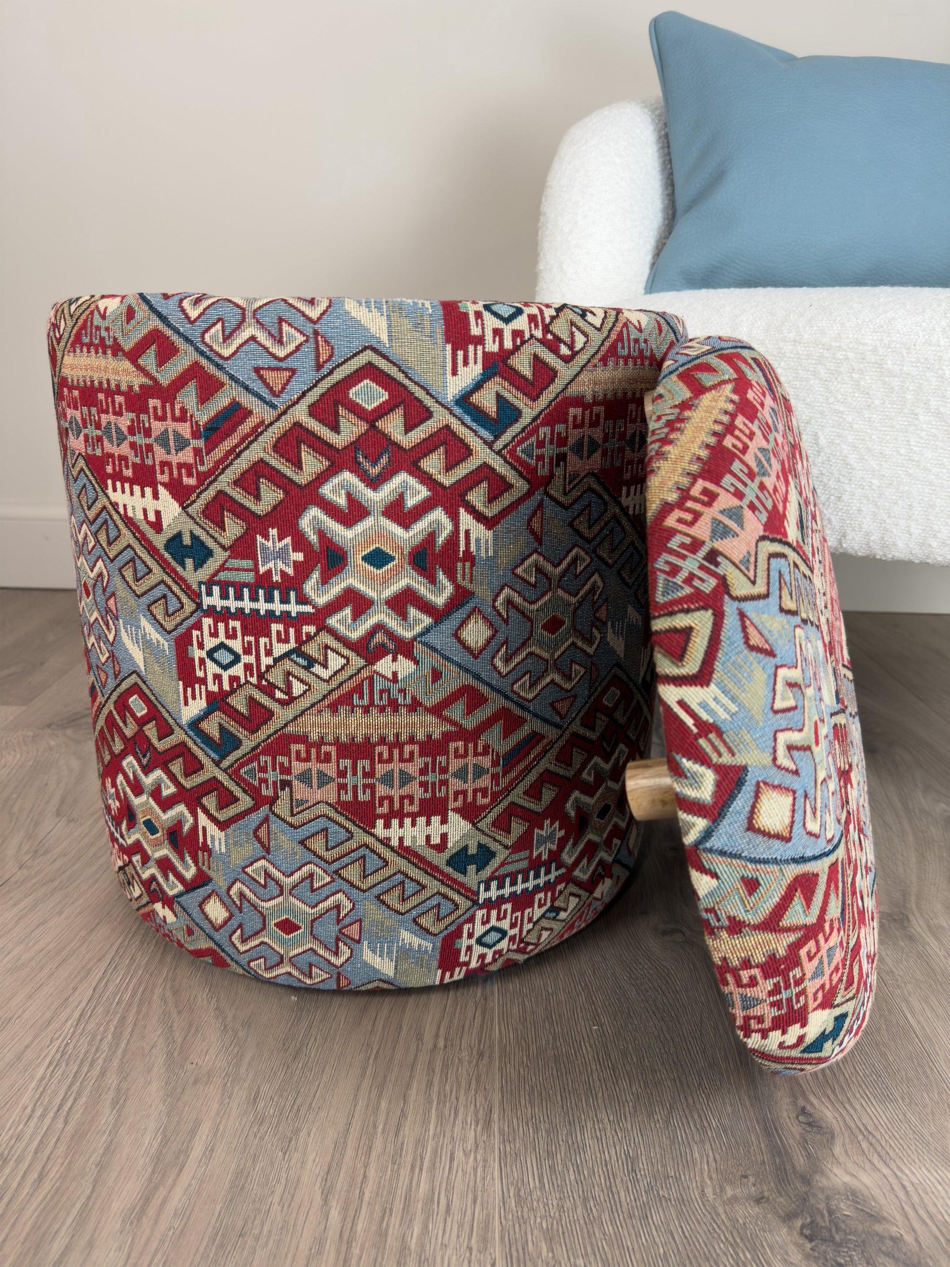 Decorative ottoman with geometric pattern on a wooden floor.