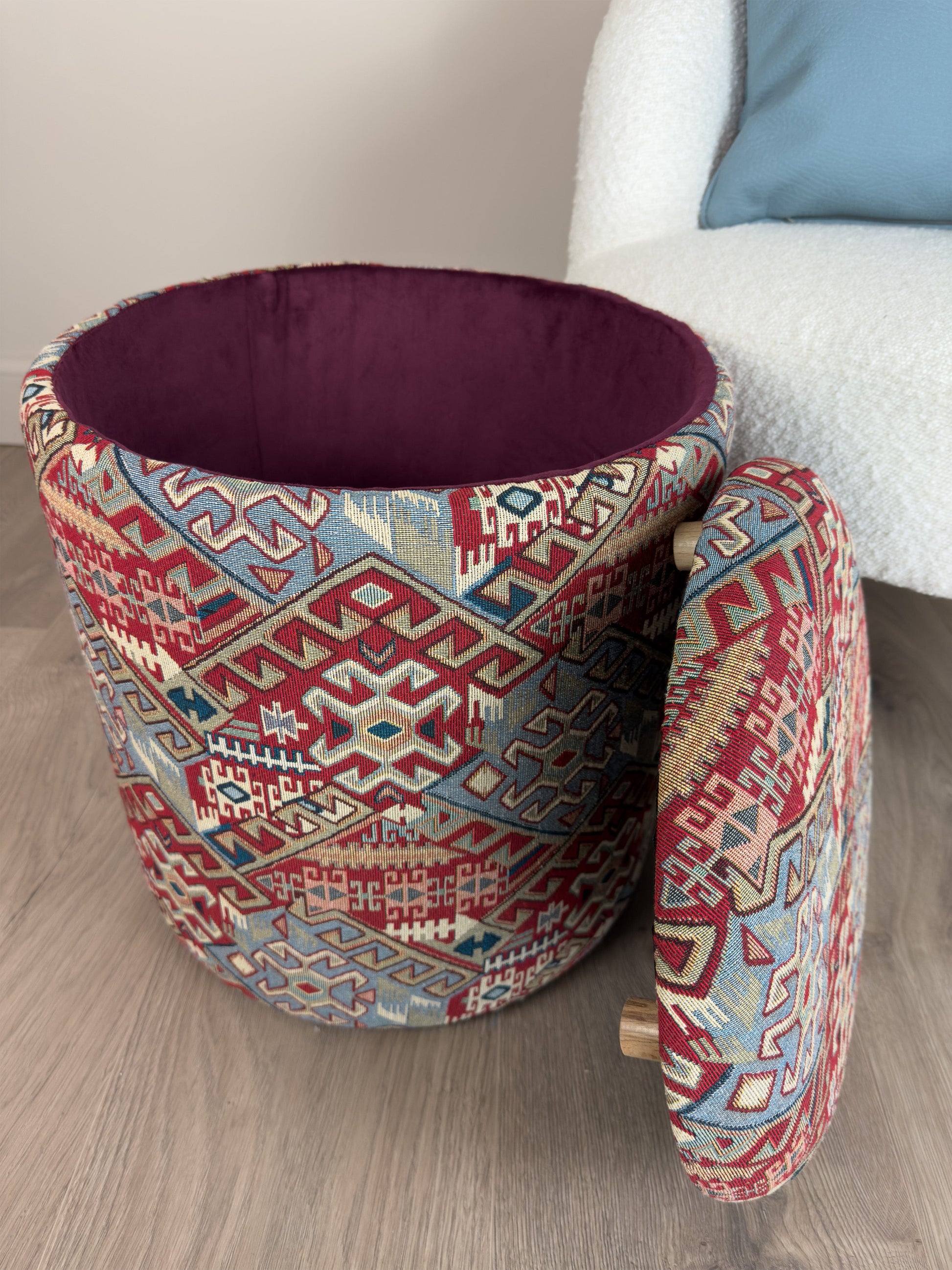 Decorative storage ottoman with geometric pattern on a wooden floor.