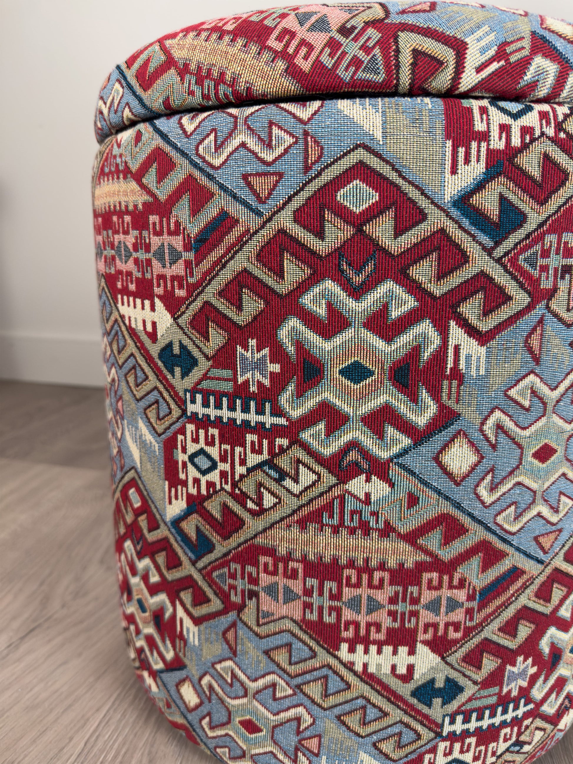 Decorative ottoman with geometric pattern on a wooden floor.