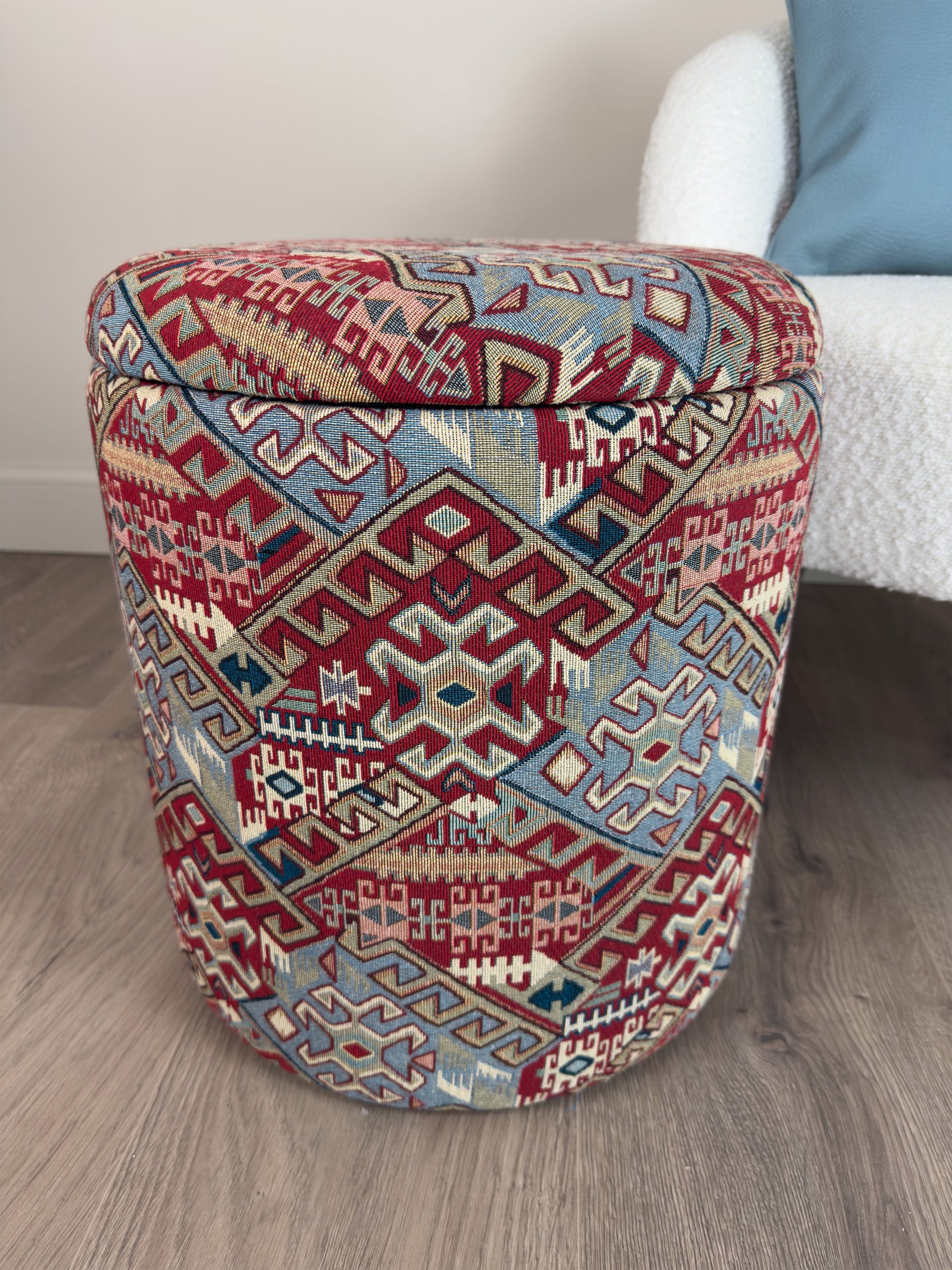 Decorative ottoman with geometric pattern on a wooden floor.