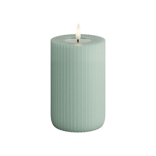 A green cylindrical LED candle with a striped pattern and a flame at the top