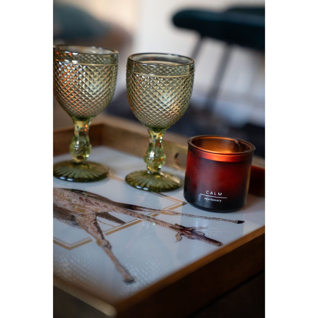 Two decorative glasses and a 'Calm' candle on a decorative giraffe tray