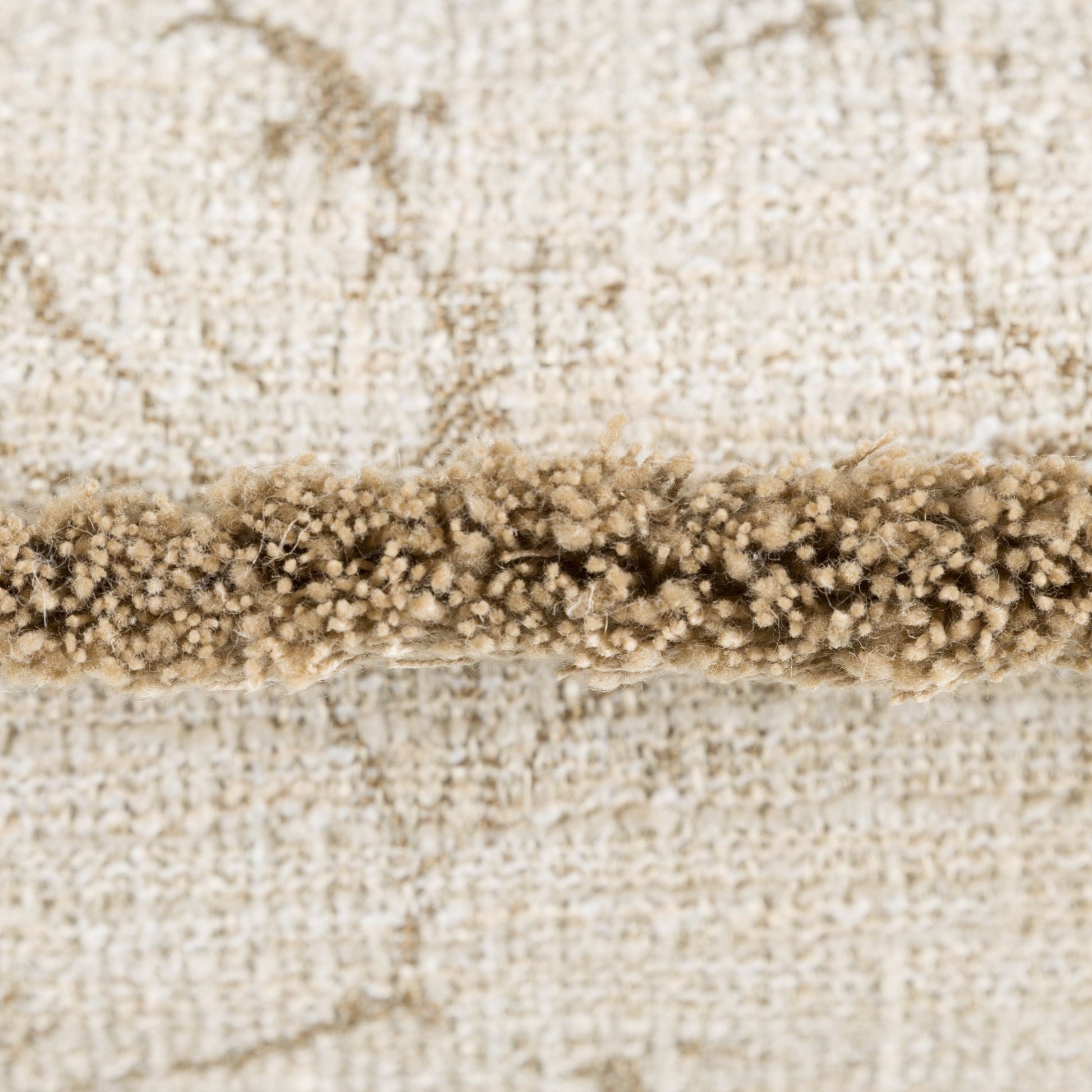 Close-up of a beige cushion with a trimmed edge and a beige pattern