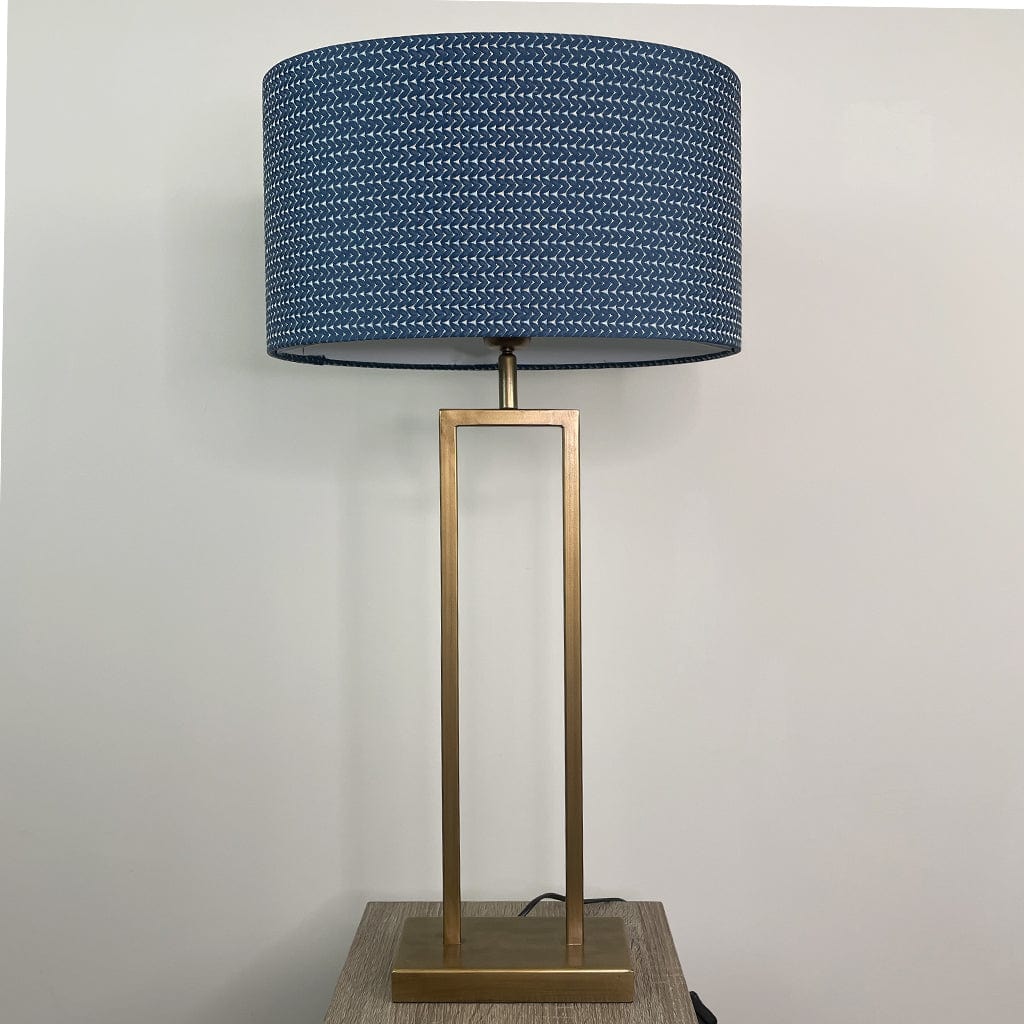Table lamp with a blue textured shade and gold base on a neutral background