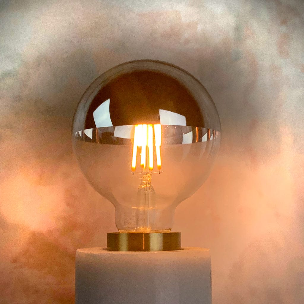 An E27 silver top 95mm globe LED light bulb with a clear glass enclosure and a metallic reflective top, in a lampholder and lit
