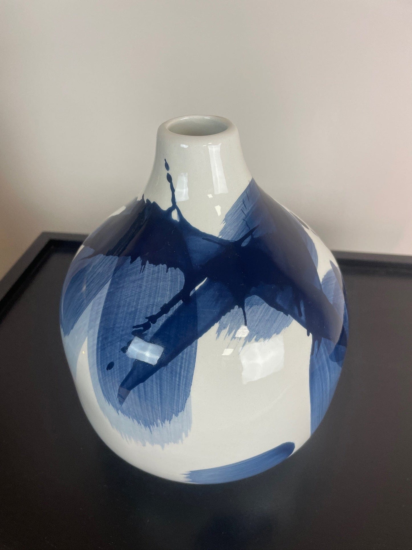 White vase with blue abstract patterns on a black surface