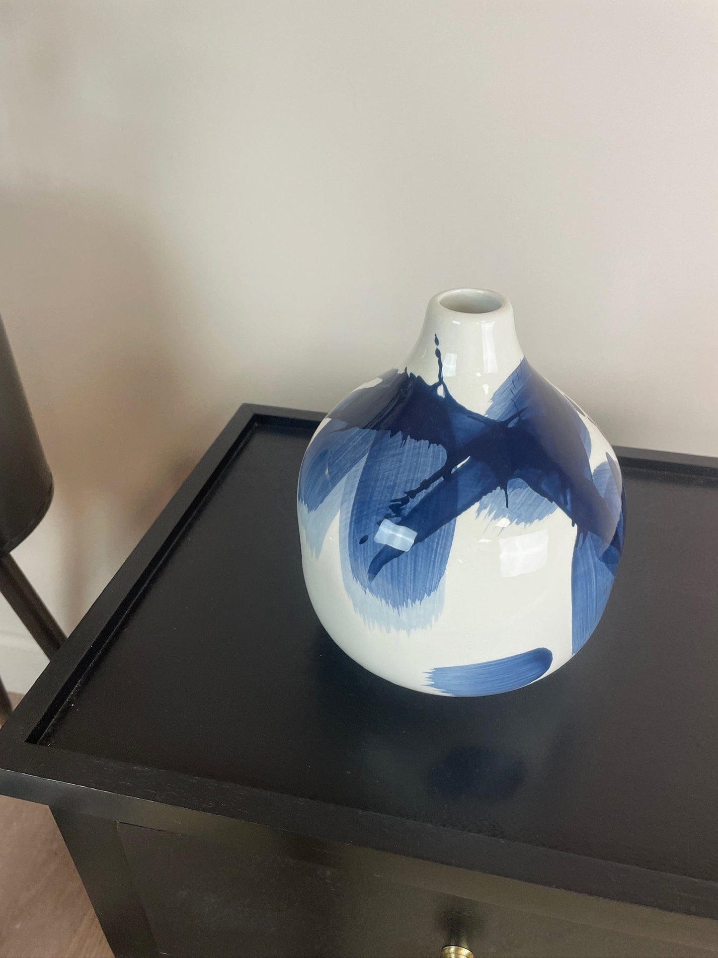 White vase with blue abstract design on a black surface