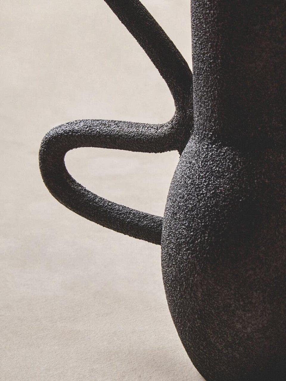 Close-up of a textured black vase on a beige background