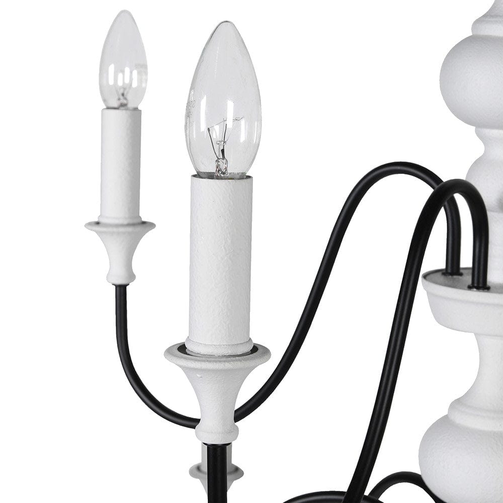 A close up of A 12-light chandelier with white center column and black curved arms, designed to mimic traditional candle holders.