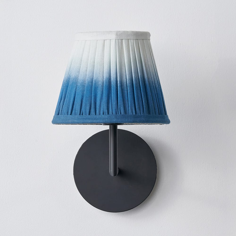Wall-mounted lamp with a pleated, gradient blue shade on a white background