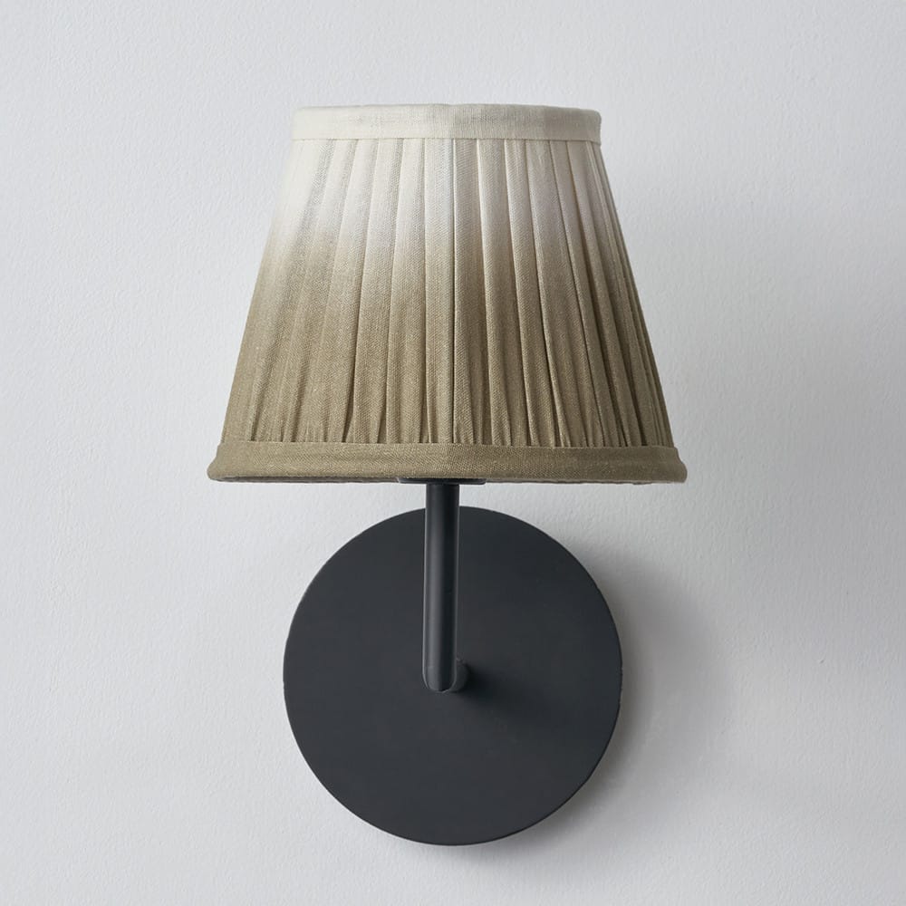 Wall-mounted lamp with a pleated beige shade on a white background