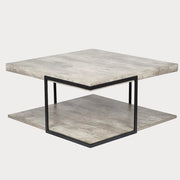 A square coffee table with a concrete effect surface and black iron frame, including a lower shelf with the same design.