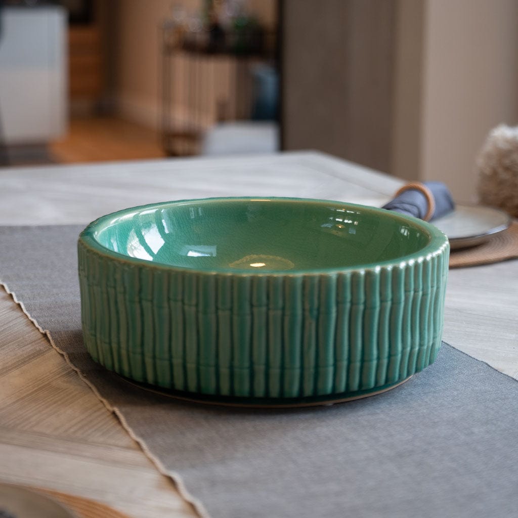 A soft aqua green ceramic bowl with a bamboo style exterior on a table setting.
