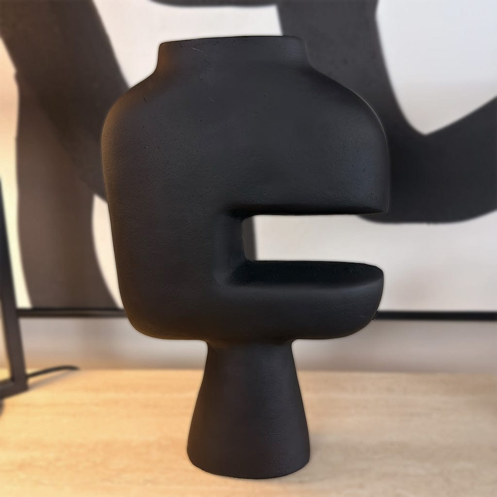 Black abstract sculpture on a wooden surface with a blurred background