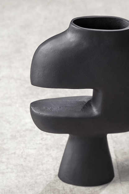 Black ceramic vase with unique design on a light gray background