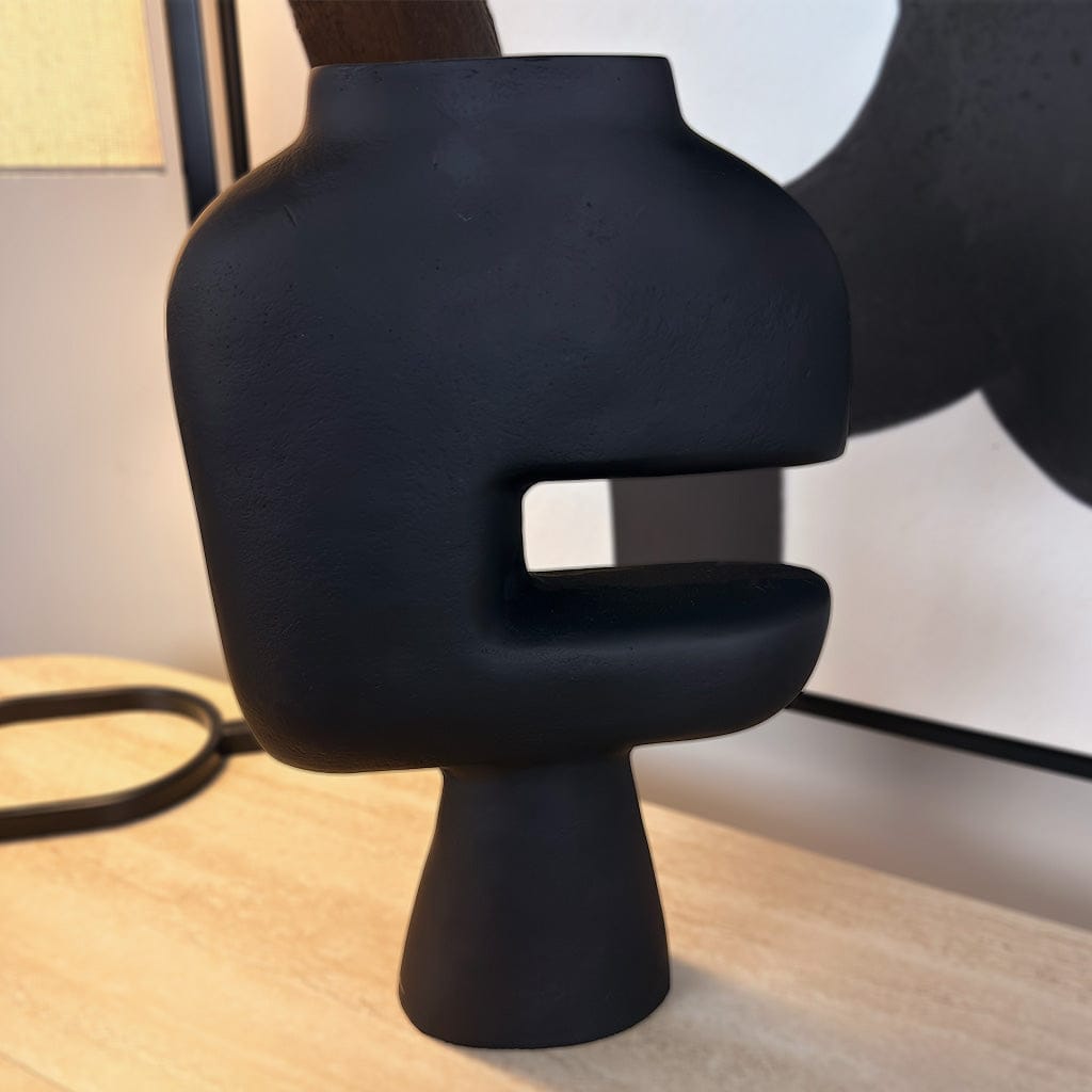 Black abstract sculpture on a wooden surface with a blurred background