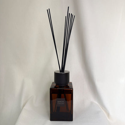 Brown diffuser bottle with black reeds on a white background