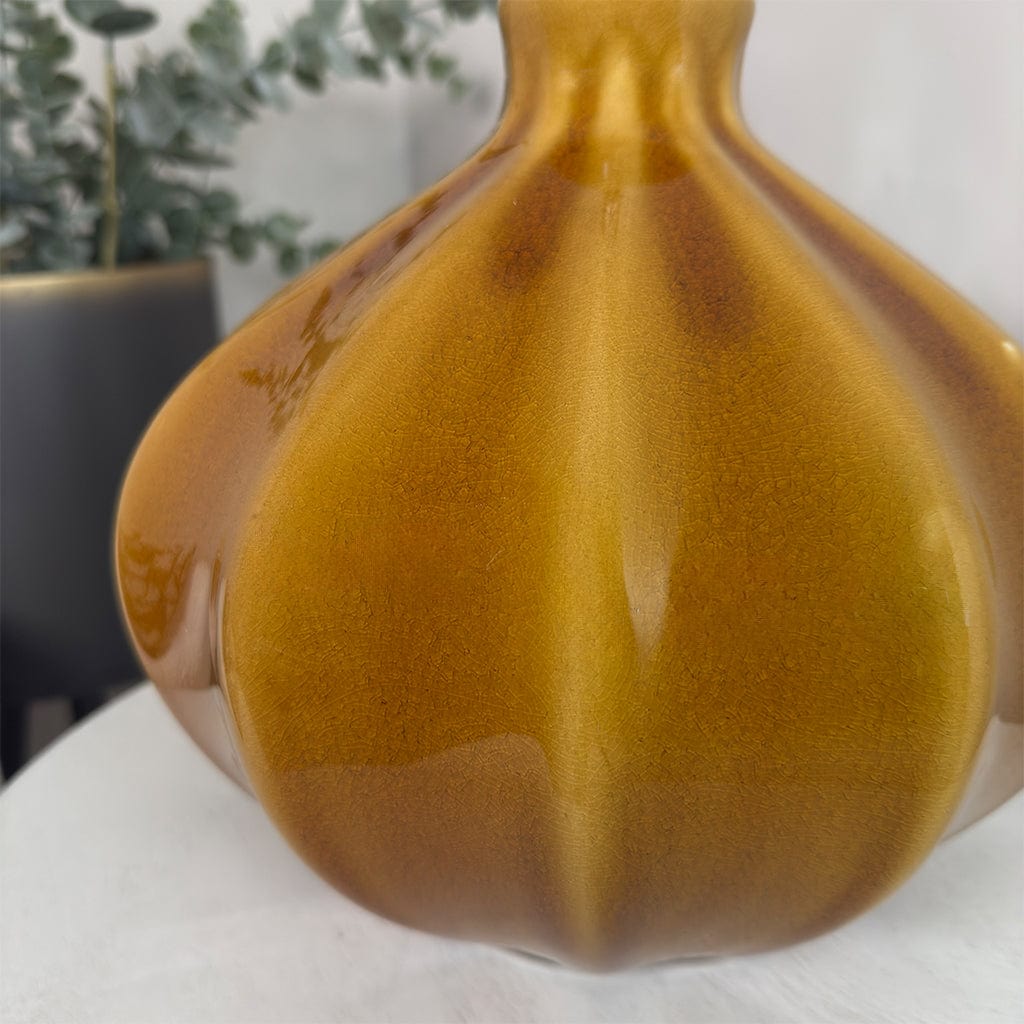 Brown ceramic vase on a white surface with a blurred background