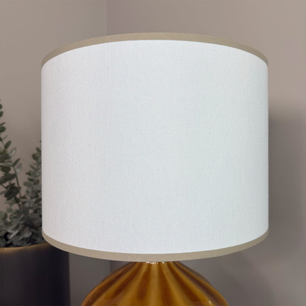 Lamp with a white shade and gold base against a neutral background