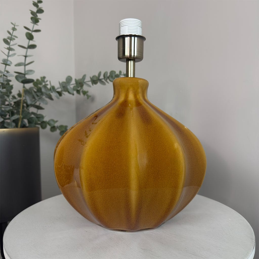 Brown decorative lamp on a white surface with a plant in the background