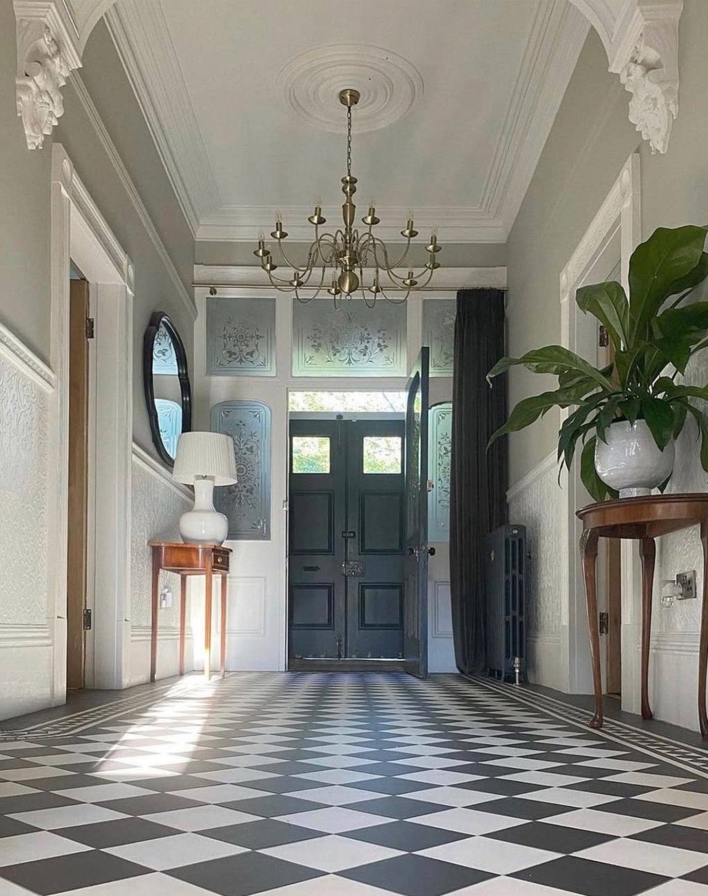 Foyer with checkered floor, chandelier, and decorative elements
