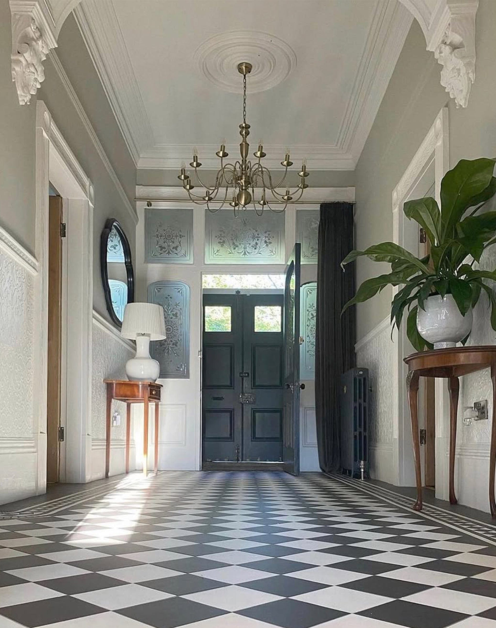 Foyer with checkered floor, chandelier, and decorative elements