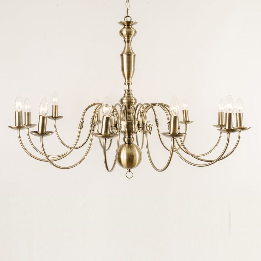 Antwerp 12 Light Antique Brass Flemish Style Chandelier with a ornate metal frame and multiple arms for candle-like lights, against a white background.