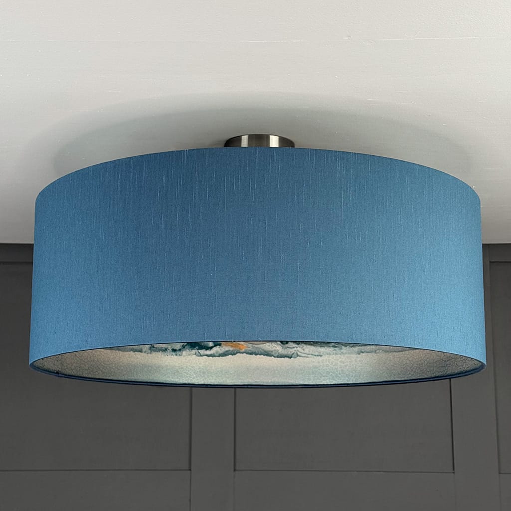 Ceiling light fixture with a blue lampshade against a gray wall.