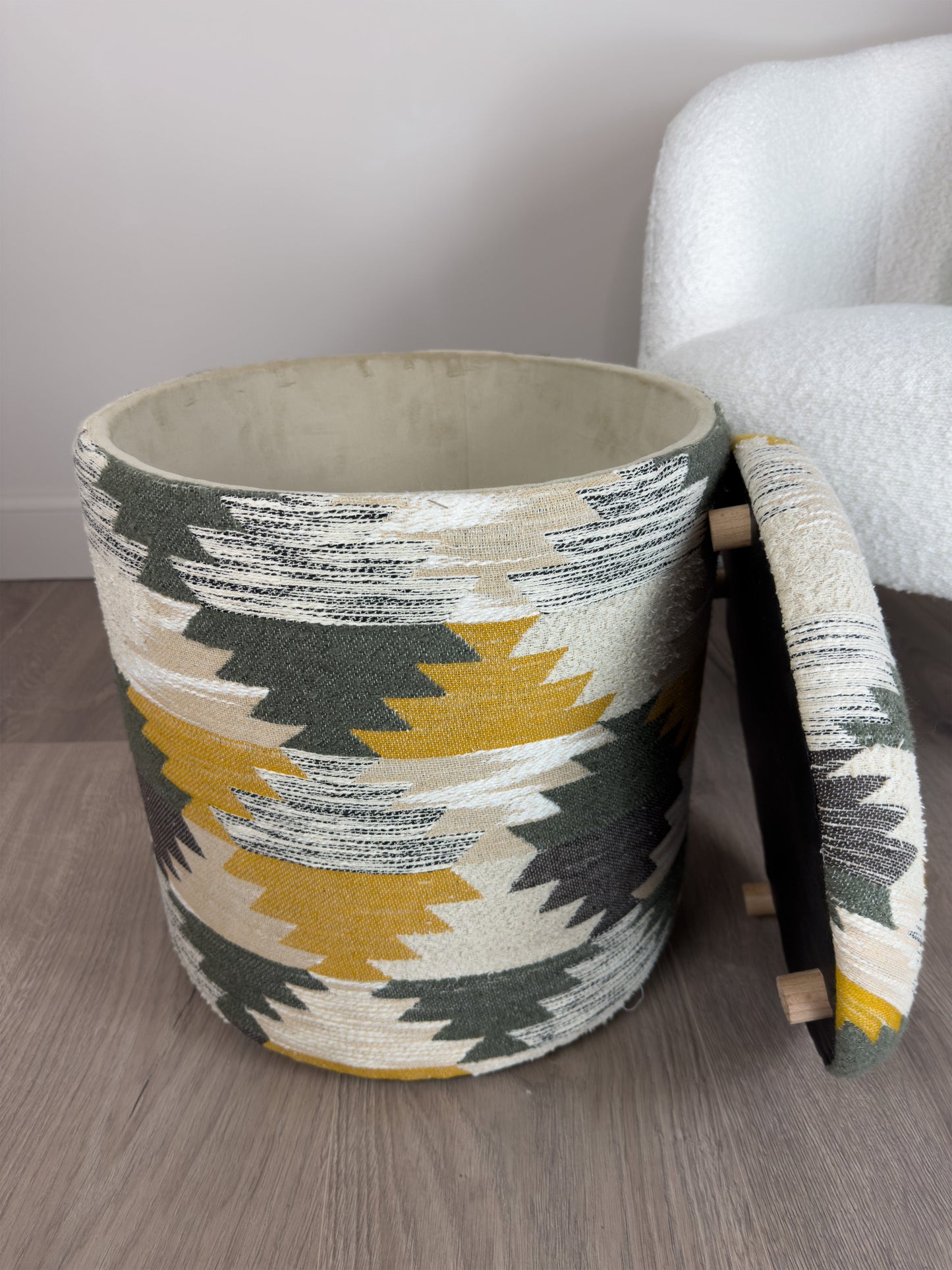 Decorative storage basket with geometric pattern next to a chair on a wooden floor.