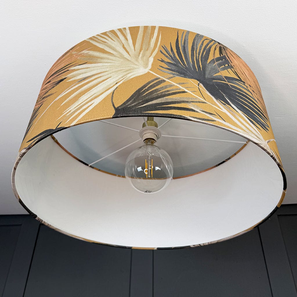 Lamp with a tropical leaf patterned shade on a plain background