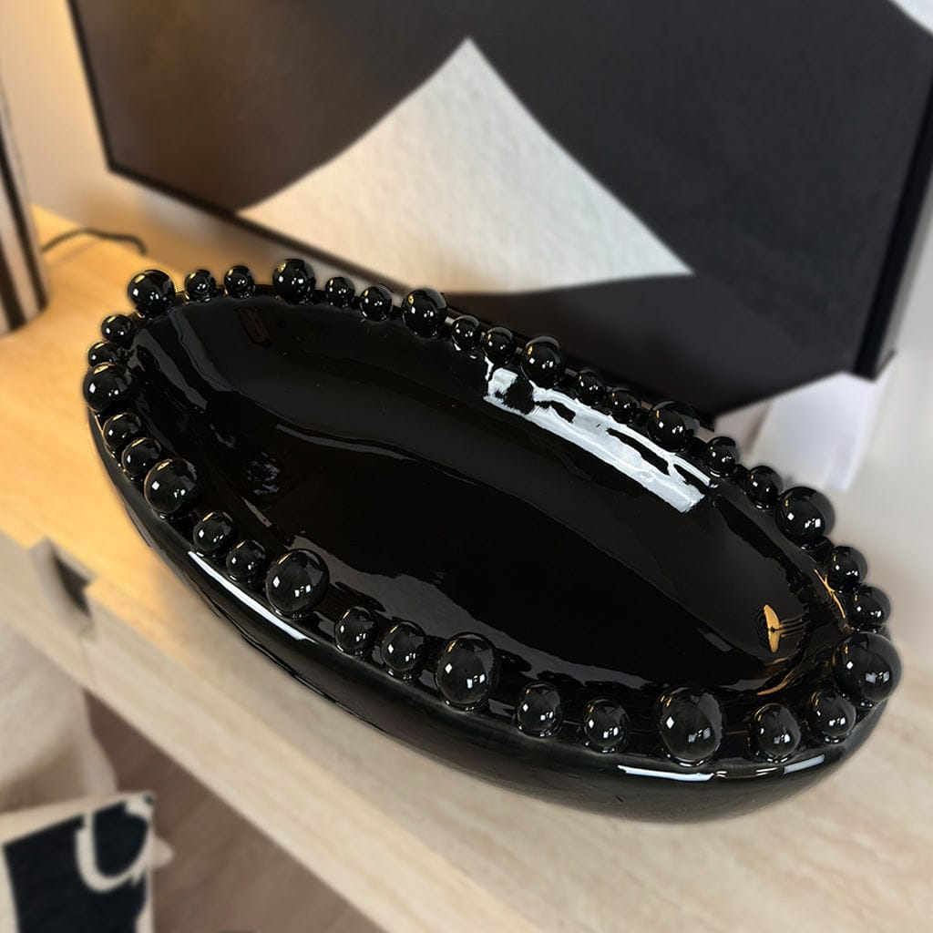 Black beaded clutch on a wooden surface with a blurred background