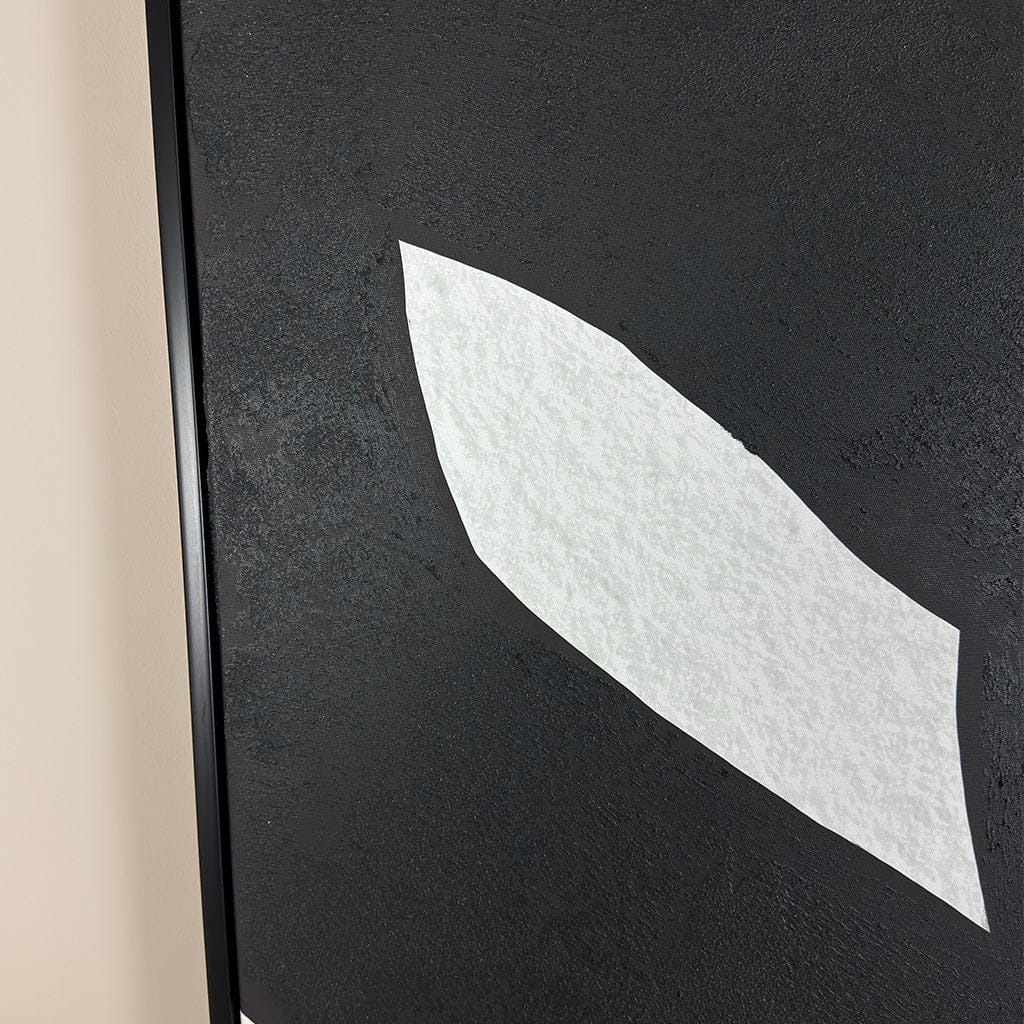 Close-up of a textured black surface with a white leaf-shaped object.