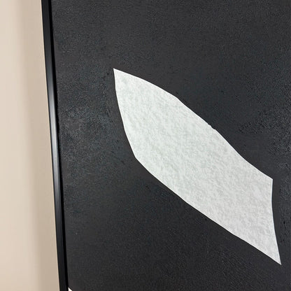 Close-up of a textured black surface with a white leaf-shaped object.