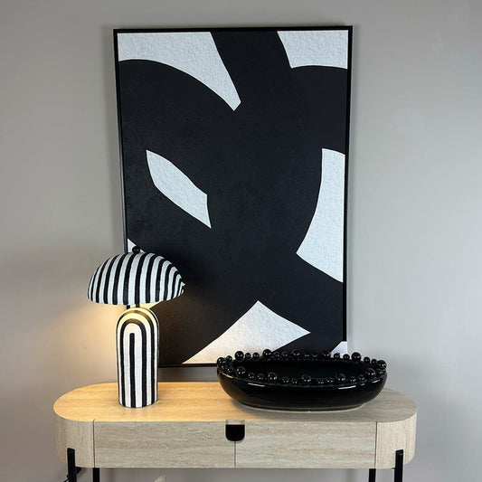 Decorative setup with abstract art, lamp, and vases on a wooden console table.