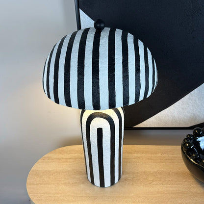 Black and white striped lamp on a wooden surface with a blurred background